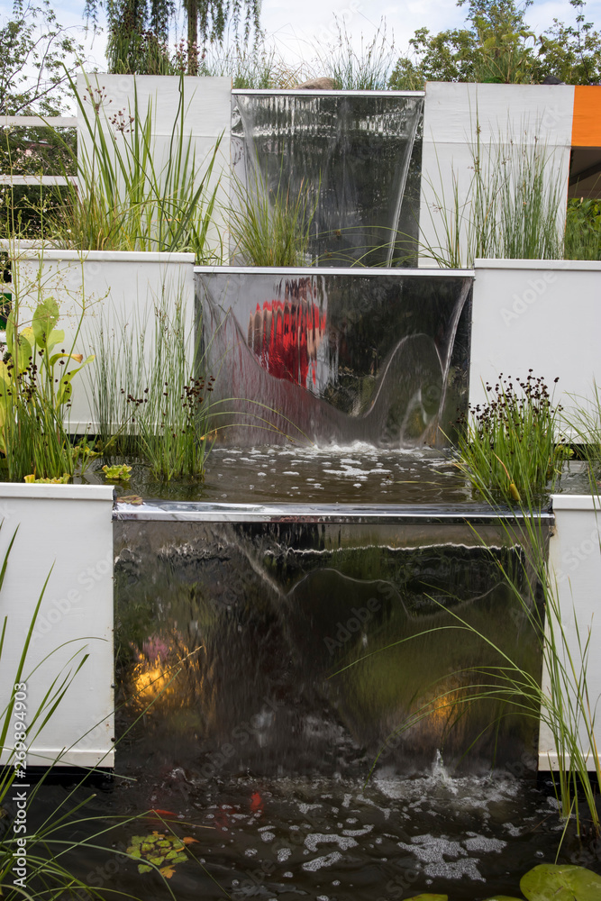 Artificial waterfall in garden with sedge and red fish as a garden decoration