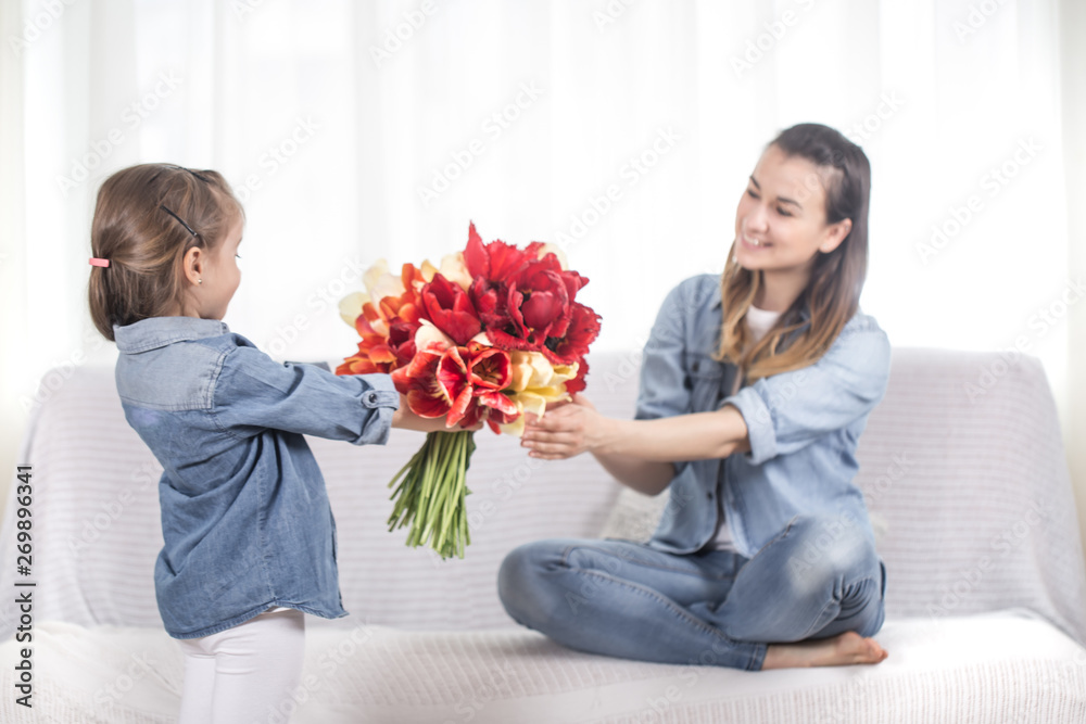 Mother's day. Little daughter with flowers congratulates her mother