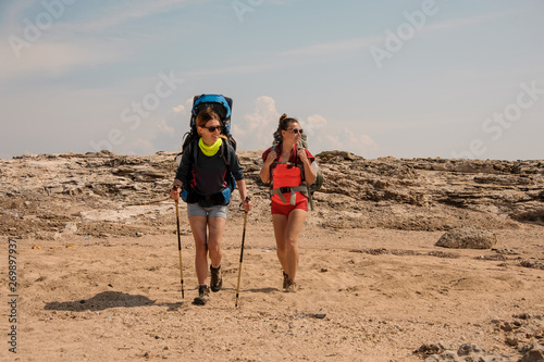 Two girls walking in the desert with hiking backpack