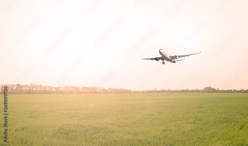 Airliner over the green field in the evening. sunset. Airliner over the green field in the evening. sunset.