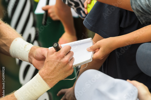 Tennis player signs autograph after win