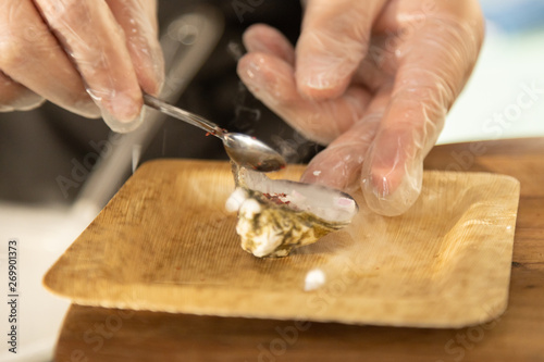 Hands in gloves adding pink peppercorns to oyster dragon breath