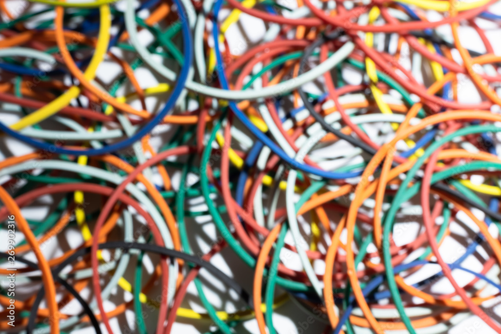 Many multi-colored rubber bands for money lie on a white surface. Defocused background for wallpaper