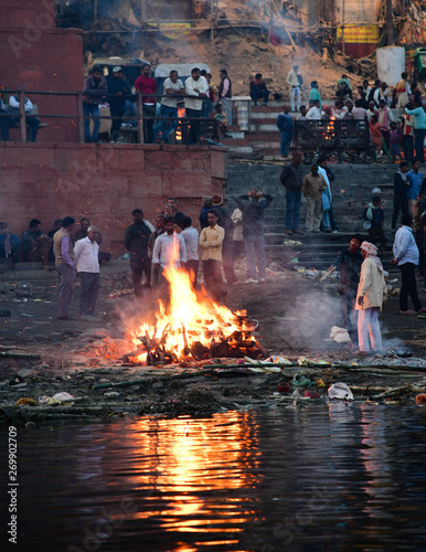 Photography A funeral pyre of a dead body being cremated by the banks of the River Ganga on