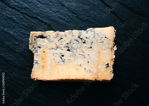 A piece of aged Italian gorgonzola cheese in a plate on a wooden background top view space for text 