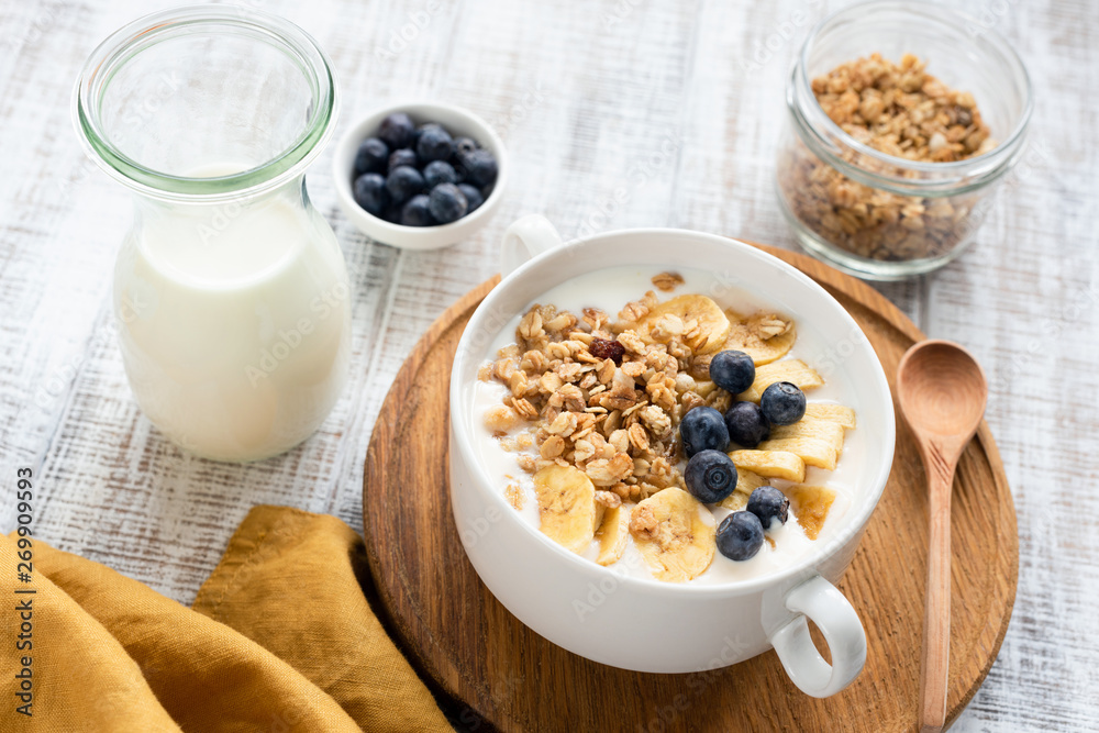 Granola bowl with milk, banana and blueberries on white wooden table background. Concept of healthy breakfast, healthy lifestyle, dieting, weight loss Granola bowl with milk, banana and blueberries on white wooden table background. Concept of healthy breakfast, healthy lifestyle, dieting, weight loss