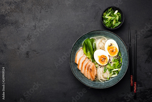 Asian ramen noodle soup with chicken on black concrete background. Top view, copy space for text