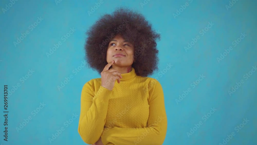 Thoughtful african woman with an afro hairstyle in a yellow jacket Thoughtful african woman with an afro hairstyle in a yellow jacket