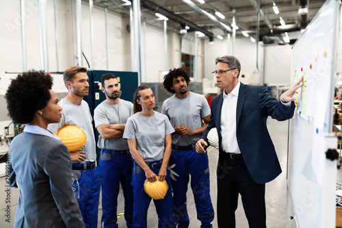 Obraz na płótnie Mature businessman explaining new strategy plans to group of employees in a factory