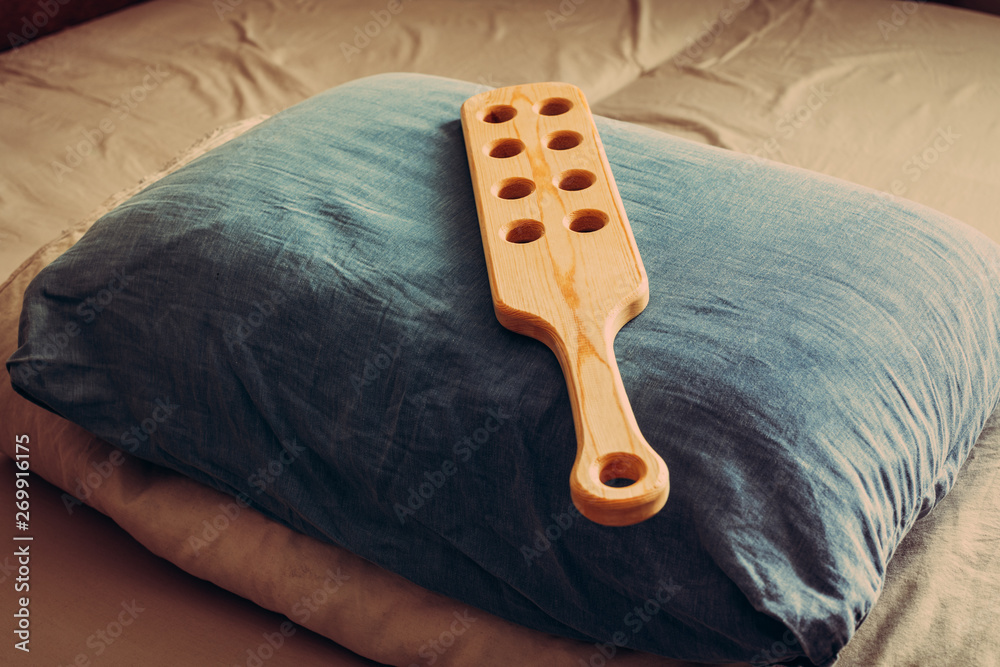Wooden paddle for spanking on pillow. Domestic discpline