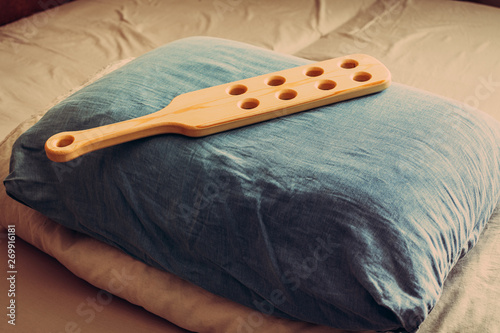 Wooden paddle for spanking on pillow. Domestic discpline. Traditional corporal punishment implements. adult role play and sex toys.