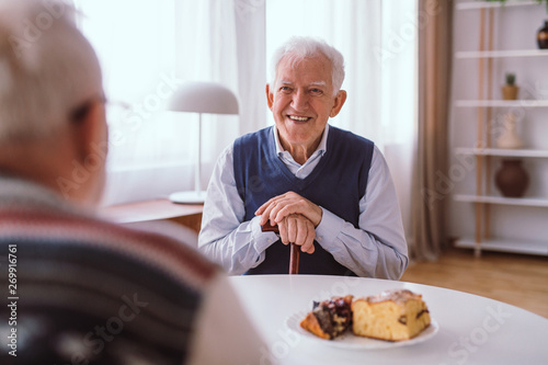 Happy senior man laughing with his old friend over the piece of cake