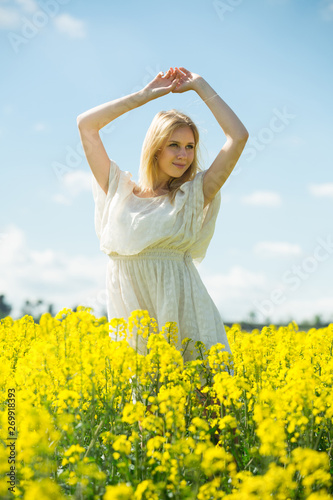 Young woman in yellow oilseed rape  field stretch oneself outdoor