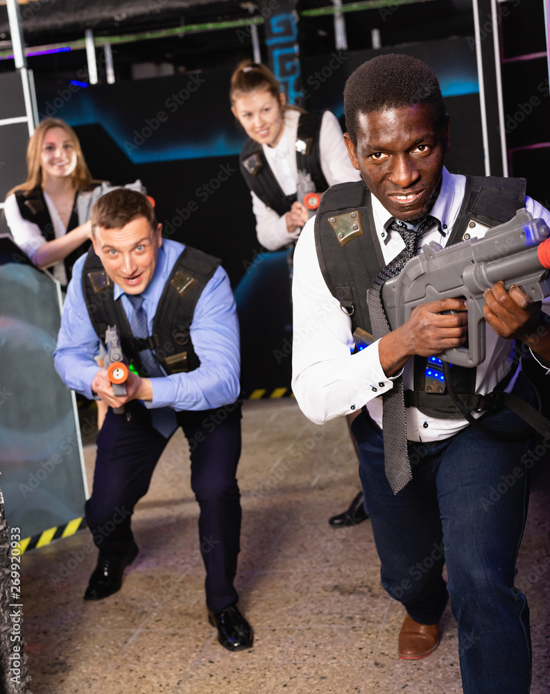 Group of colleagues holding laser pistols playing laser tag game