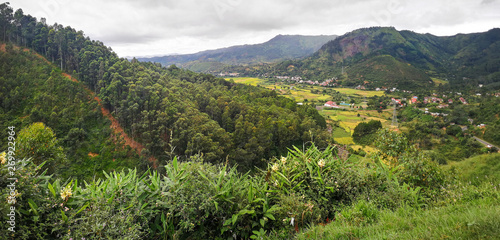 Typical Madagascar landscape at Mandraka region. Hills covered with green foliage, small villages in distance, on overcast day photo