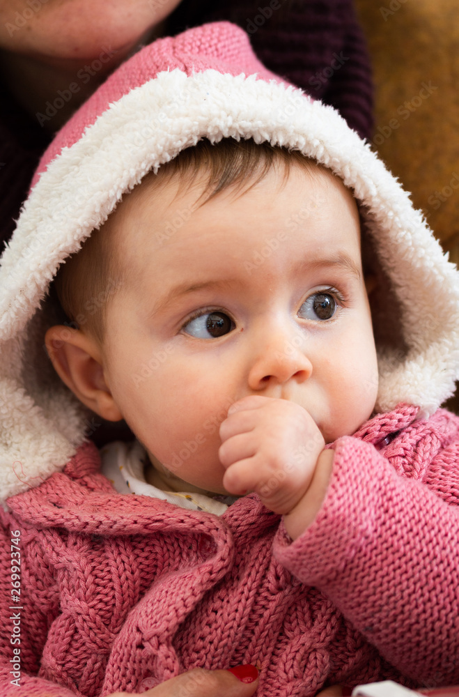 A Cute Baby Sucks his Thumb Wearing a Pink Wool Jacket A Cute Baby Sucks his Thumb Wearing a Pink Wool Jacket