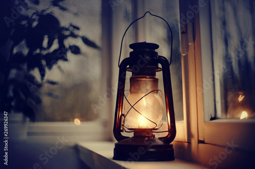 Vintage kerosene lamp stands on a white windowsill