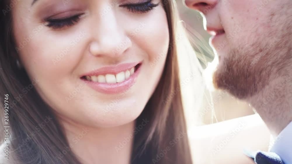 Romantic wedding moment, couple of bride and groom hug while on a walk in the park. Loving wedding couple outdoor. He is kissing her Romantic wedding moment, couple of bride and groom hug while on a walk in the park. Loving wedding couple outdoor. He is kissing her