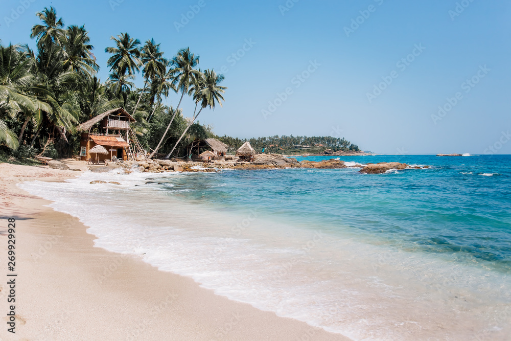 White sand & blue water in Tangalle. Goyambokka beach with palm & house on the shore, in the southern province of Sri Lanka. Majestic bay in Indian Ocean. Waves breaking on the most beautiful stones.