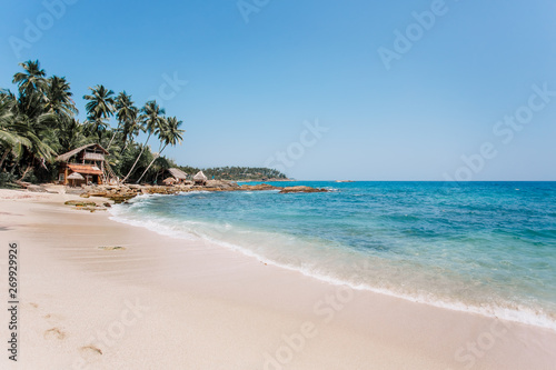 White sand & blue water in Tangalle. Goyambokka beach with palm & house on the shore, in the southern province of Sri Lanka. Majestic bay in Indian Ocean. Waves breaking on the most beautiful stones.