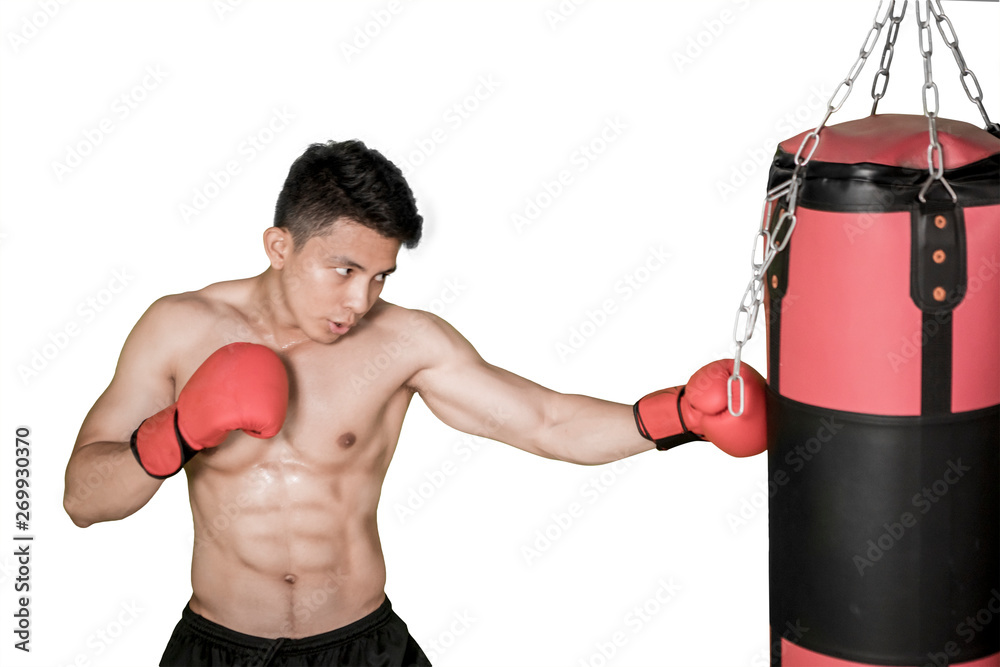 Muscled man hits on a boxing bag in the studio