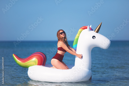 beautiful girl in bikini swimming on giant unicorn during summer vacation © Olesia Bilkei