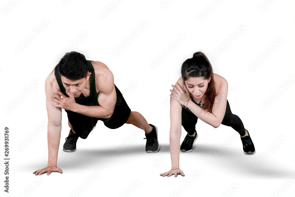 Obraz premium Young couple doing plank exercises on studio