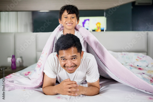 Young man playing with his son under a blanket