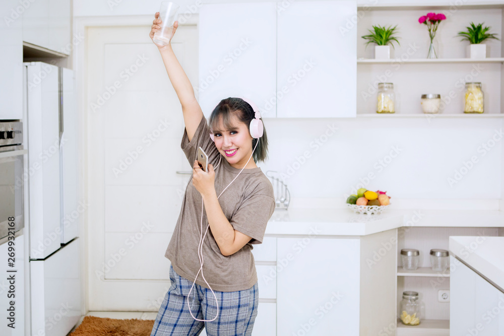 Young woman enjoying music in the kitchen Young woman enjoying music in the kitchen