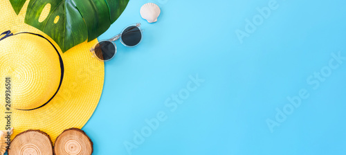 summer blue banner with yellow hat ,sunglasses,seashell and monstera leaf on blue background top view.