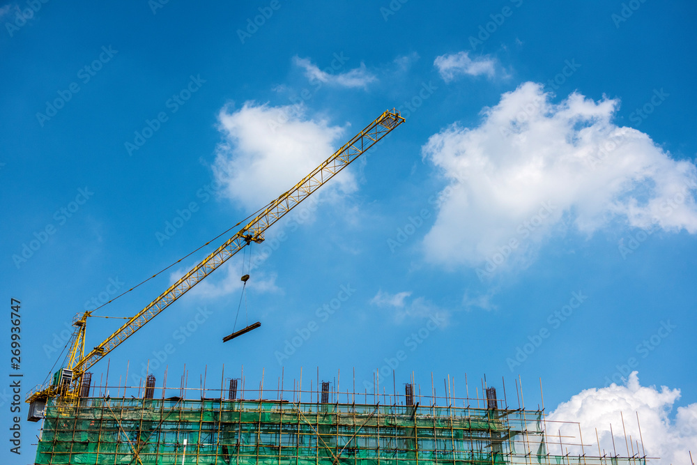 Tower crane at the construction site of blue sky and white clouds.