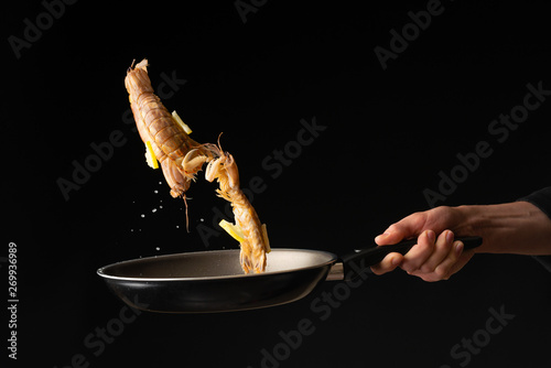 Chef prepares sea food, mantis shrimp with lemon, East Asian cuisine, dilikates, on a black background, horizontal photo, close-up photo