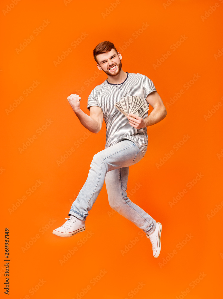 Lucky man celebrating and jumping on orange background