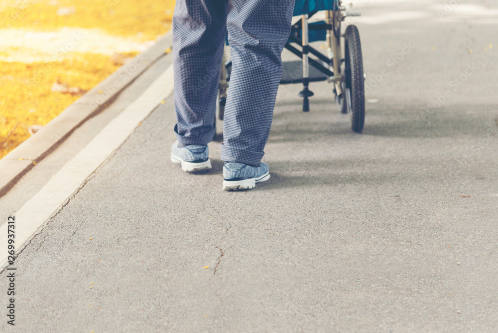 Senior woman try to exercise by walk around the park by using wheelchair. Health care concept