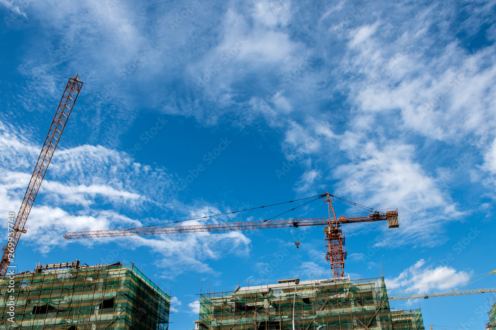 Tower crane at the construction site of blue sky and white clouds. Tower crane at the construction site of blue sky and white clouds.