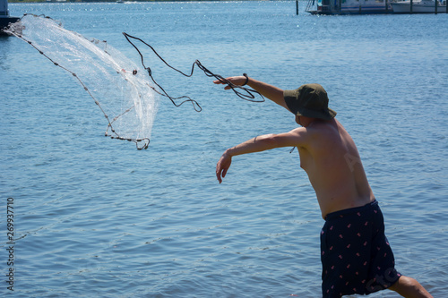Fototapeta Naklejka Na Ścianę i Meble -  Man that Hand Launches the Fishnet at Sea