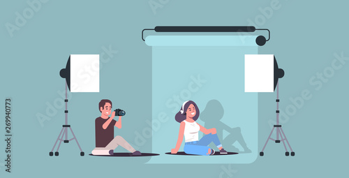 professional photographer using camera man shooting beautiful sexy woman model sitting posing in modern photo studio interior horizontal full length flat