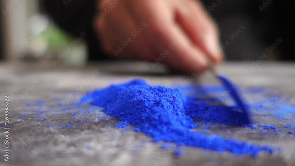 Artist prepering blue powder pigment on table in workshop, closeup