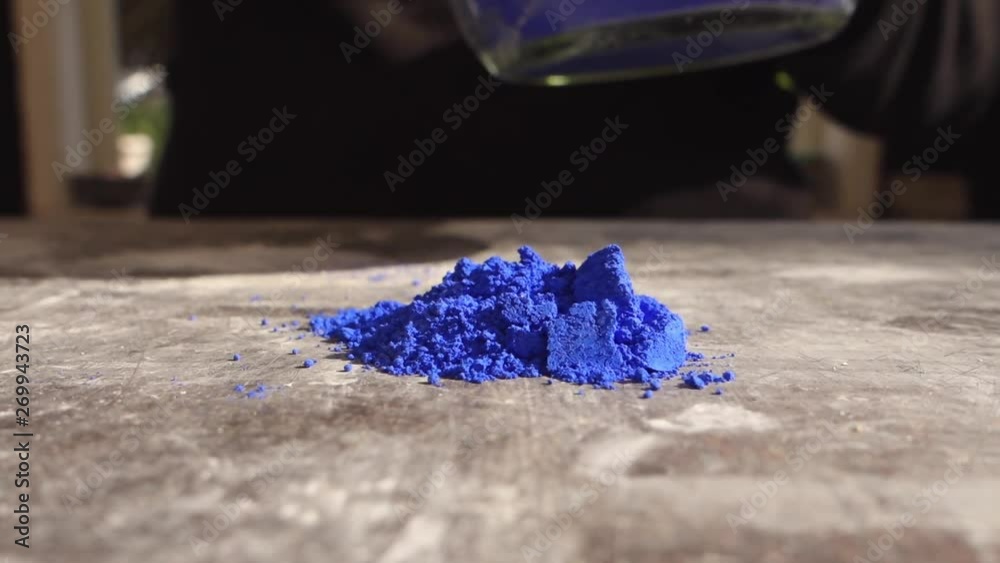 Artist prepering blue powder pigment on table in workshop, closeup