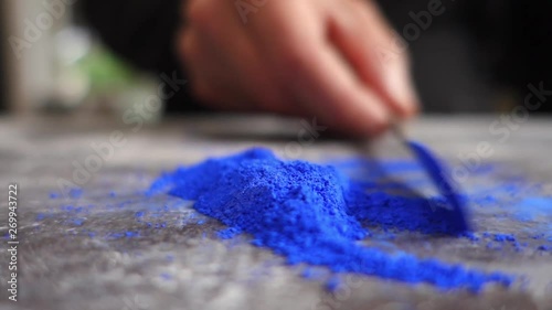 Artist prepering blue powder pigment on table in workshop, closeup