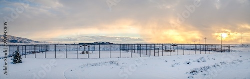 Tennis courts inside a chain link fence and blanketed with snow in winter © Jason