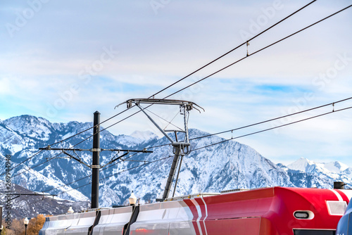 Shiny exterior of a red and white train connected to thick cable wires