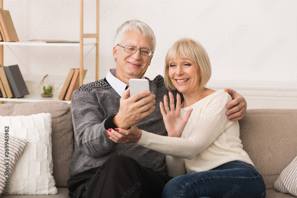 Happy Senior Couple Making Video Call And Waving To Caller Happy Senior Couple Making Video Call And Waving To Caller