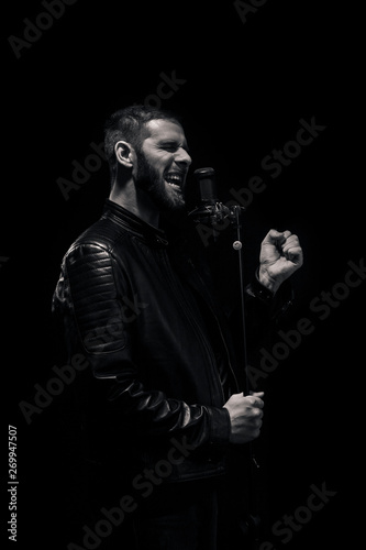 rock musician singing on a microphone. Shot on a black background. Black and white image.