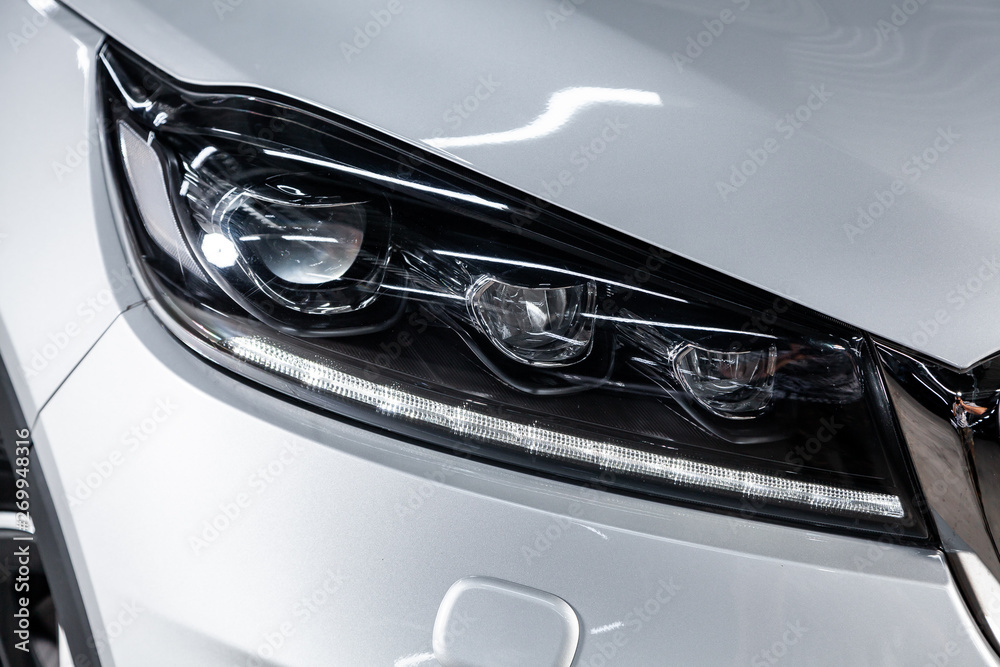 Concept of modern car detailing and light technology.  Close up of headlight on expensive car with projector lens