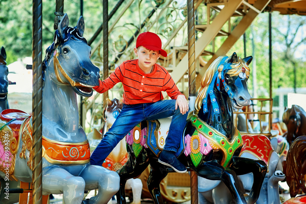 Beautiful boy posing on the carousel . The concept of children's summer holiday