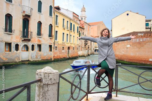Happy girl in Venice, Italy. Young enjoying traveler woman on narrow canal and street in Venice. Vacation in Italy
