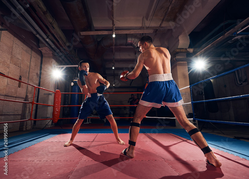 Two athlete sportsmen boxers exercising boxing in the ring at the sport club