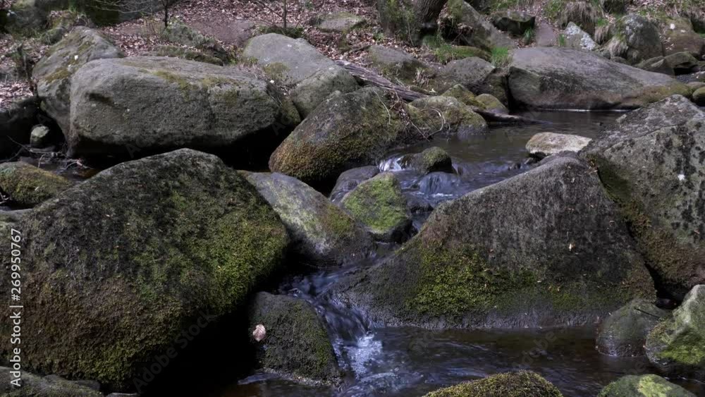 Slow pan right view of water flowing over rocks in Padley Gorge in Peak District National Park, United Kingdom Slow pan right view of water flowing over rocks in Padley Gorge in Peak District National Park, United Kingdom