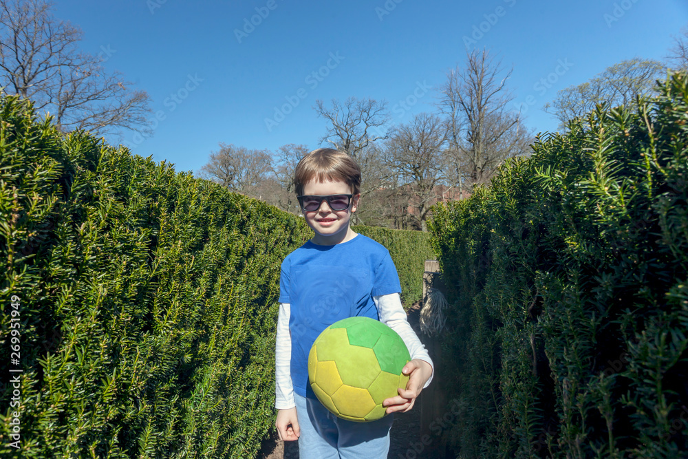 Naklejka premium Five year old boy posing with ball in Bush Labyrinth at Slottsskogen park